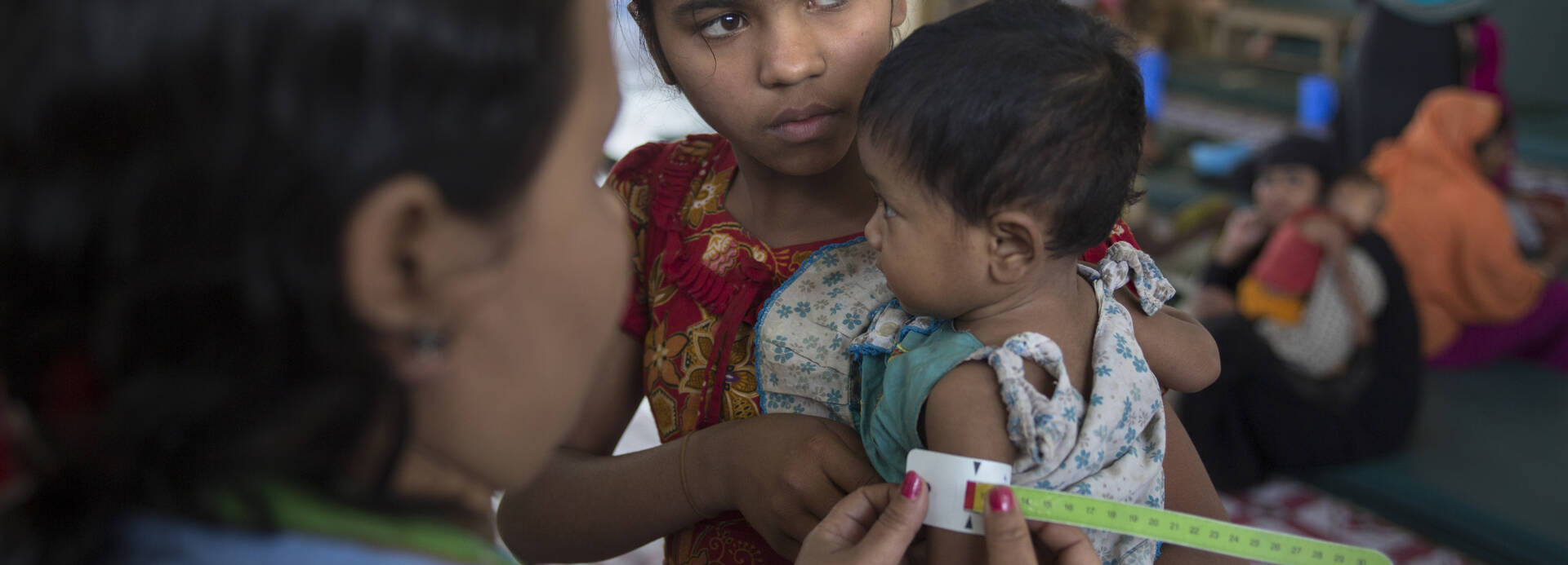 Mitarbeiterin von Aktion gegen den Hunger misst Kind mit dem MUAC-Band in Bangladesch Mitarbeiterin von Aktion gegen den Hunger misst Kind mit dem MUAC-Band in Bangladesch