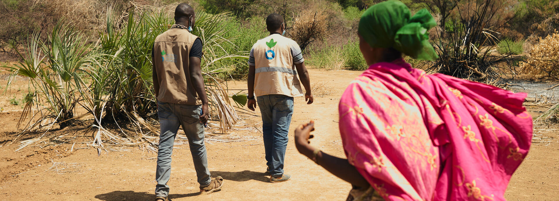 Frau und Mitarbeiter von Aktion gegen den Hunger in trockener Landschaft in Kenia