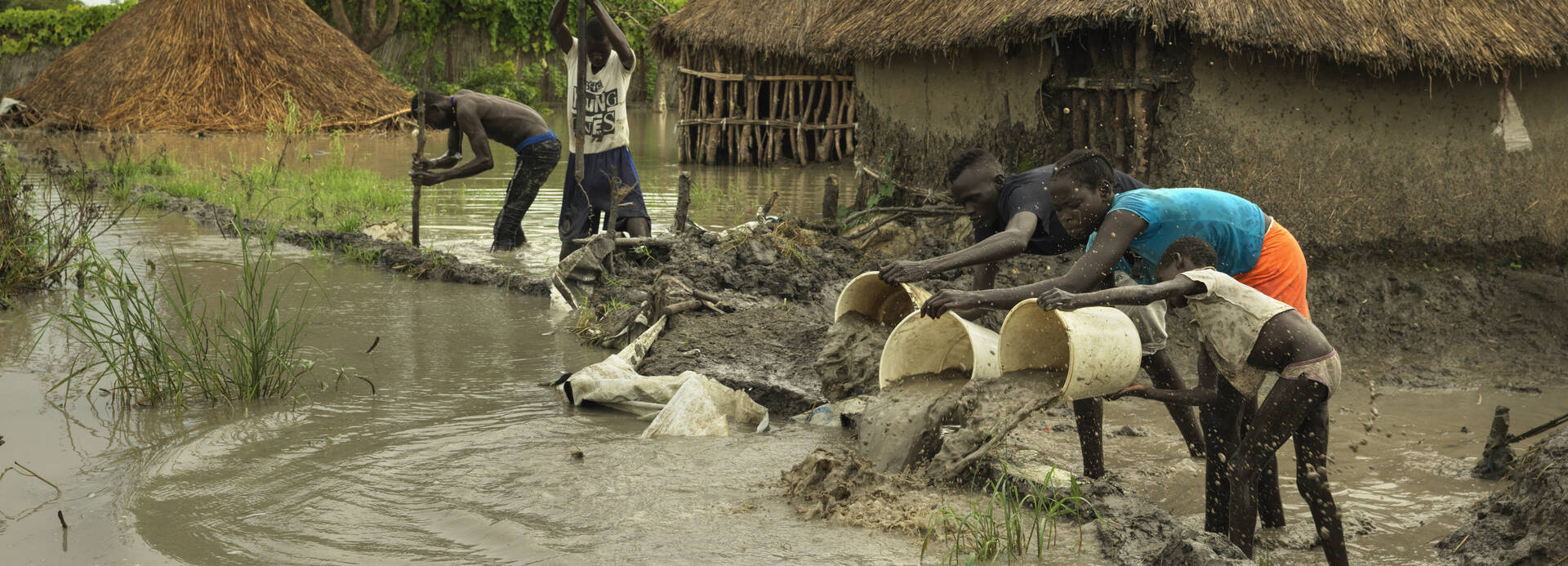 Flut im Südsudan: Eine Familie versucht, mit Eimern das Flutwasser aus dem Dorf vor einen selbstgebauten kleinen Staudamm zu schöpfen.