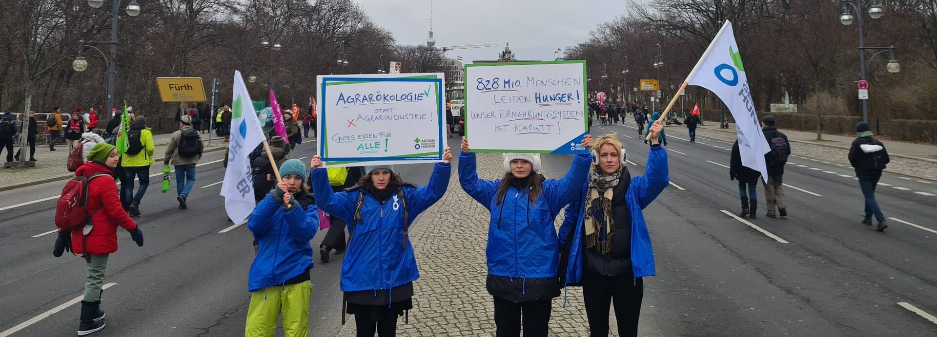 Vier Mitarbeiterinnen von Aktion gegen den Hunger halten im Januar 2023 Demoschilder und Flaggen auf der "Wir haben es satt!"-Demo hoch. Vier Mitarbeiterinnen von Aktion gegen den Hunger halten im Januar 2023 Demoschilder und Flaggen auf der "Wir haben es satt!"-Demo hoch.
