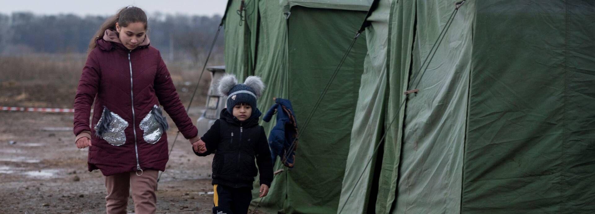 Eine Mutter geht mit ihrem Sohn durch ein Aufnahmelager an der ukrainisch-moldawischen Grenze.