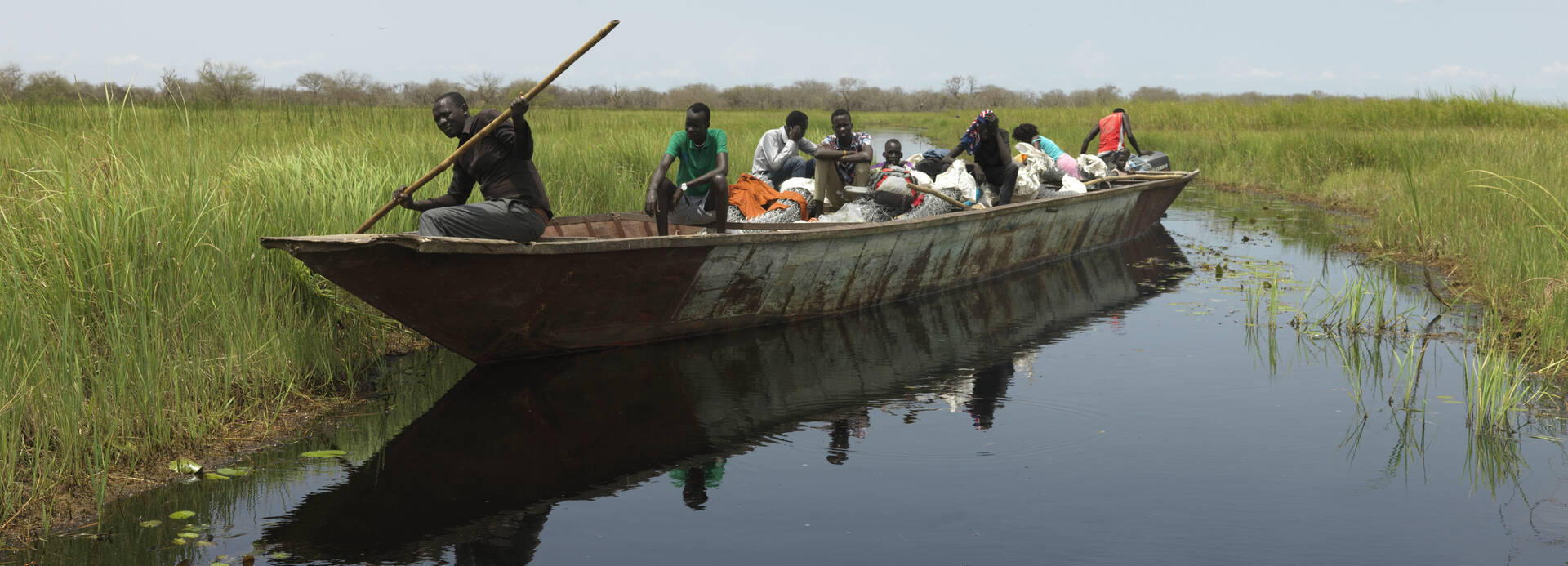 Menschen aus dem Südsudan befahren mit einem großen Boot eine der neuen Wasserstraßen in Paguir