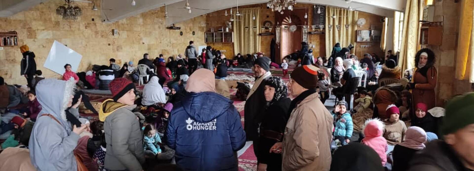 Eine Mitarbeiterin von Aktion gegen den Hunger spricht in einer syrischen Sammelunterkunft mit Menschen, die nach den schweren Erdbeben Zuflucht suchen.