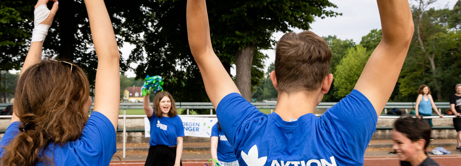 Mitarbeitende feuern Kinder beim Spendenlauf an Mitarbeitende feuern Kinder beim Spendenlauf an