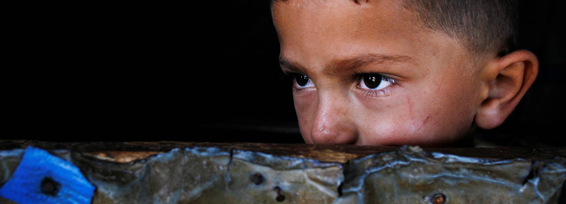 Ein kleiner Junge aus dem Libanon guckt abwartend über eine Mauer