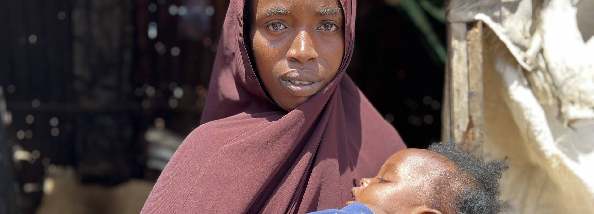 Ifrah aus Somalia hält ihre neun Monate alte Tochter in den Armen. Sie stehen vor der Küche, die heute kalt geblieben ist.