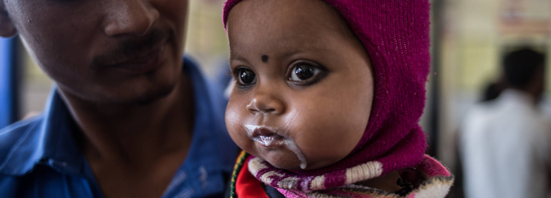 Bhumika bekommt in der Klinik in Indien Aufbaunahrung in einem Becher von ihrem Vater. Bhumika bekommt in der Klinik in Indien Aufbaunahrung in einem Becher von ihrem Vater.