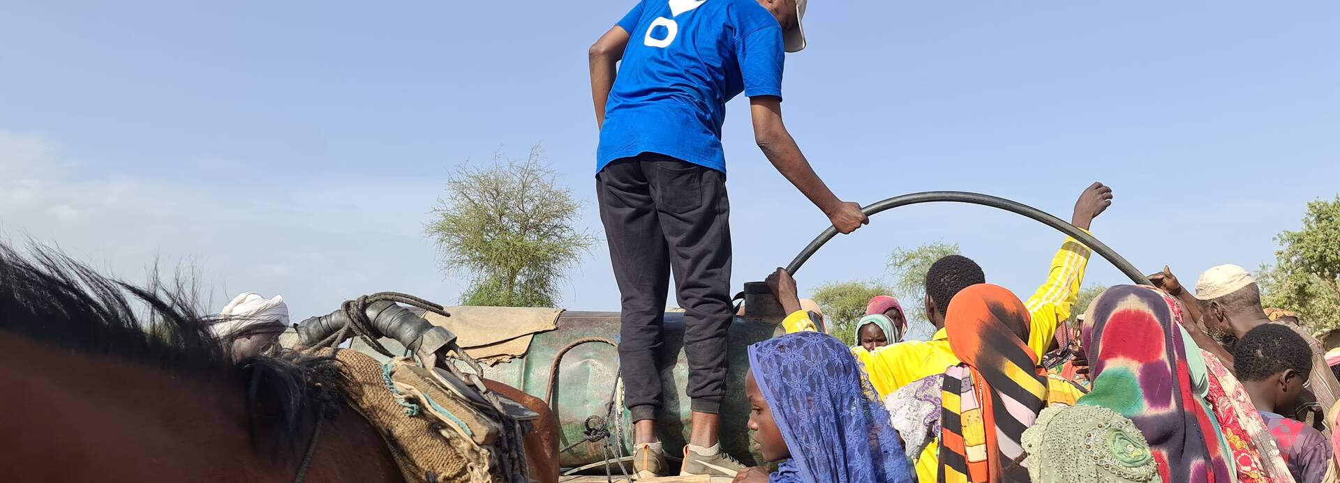 Ein Mitarbeiter von Aktion gegen den Hunger versorgt Geflüchtete aus dem Sudan mit Trinkwasser.