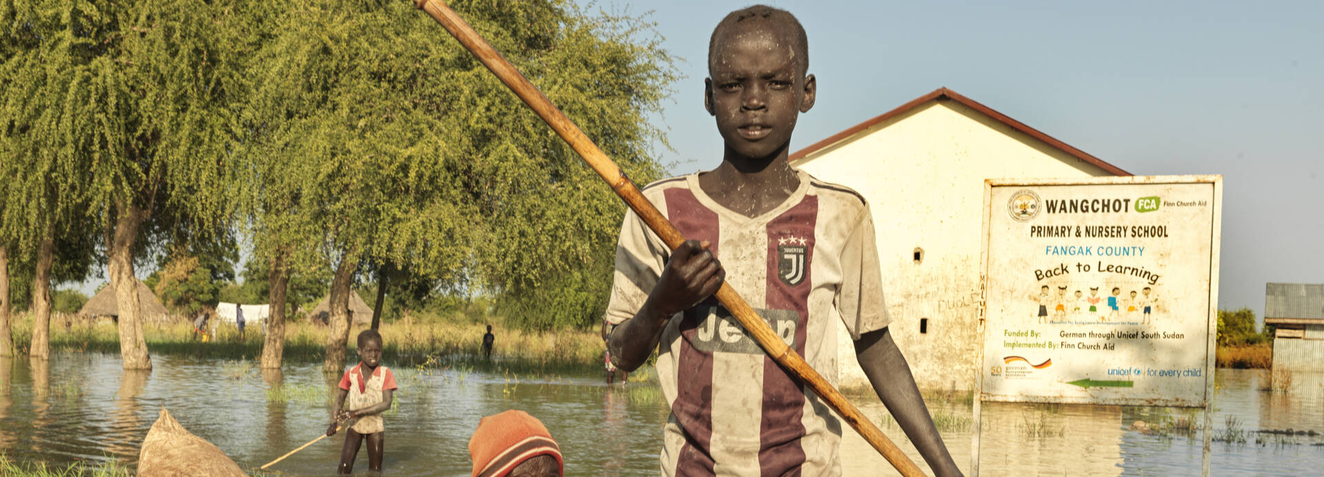 Ein Junge fährt mit einer älteren Frau in einem Baumstamm-Boot durch ein überflutetes Gebiet im Südsudan. Ein Junge fährt mit einer älteren Frau in einem Baumstamm-Boot durch ein überflutetes Gebiet im Südsudan.