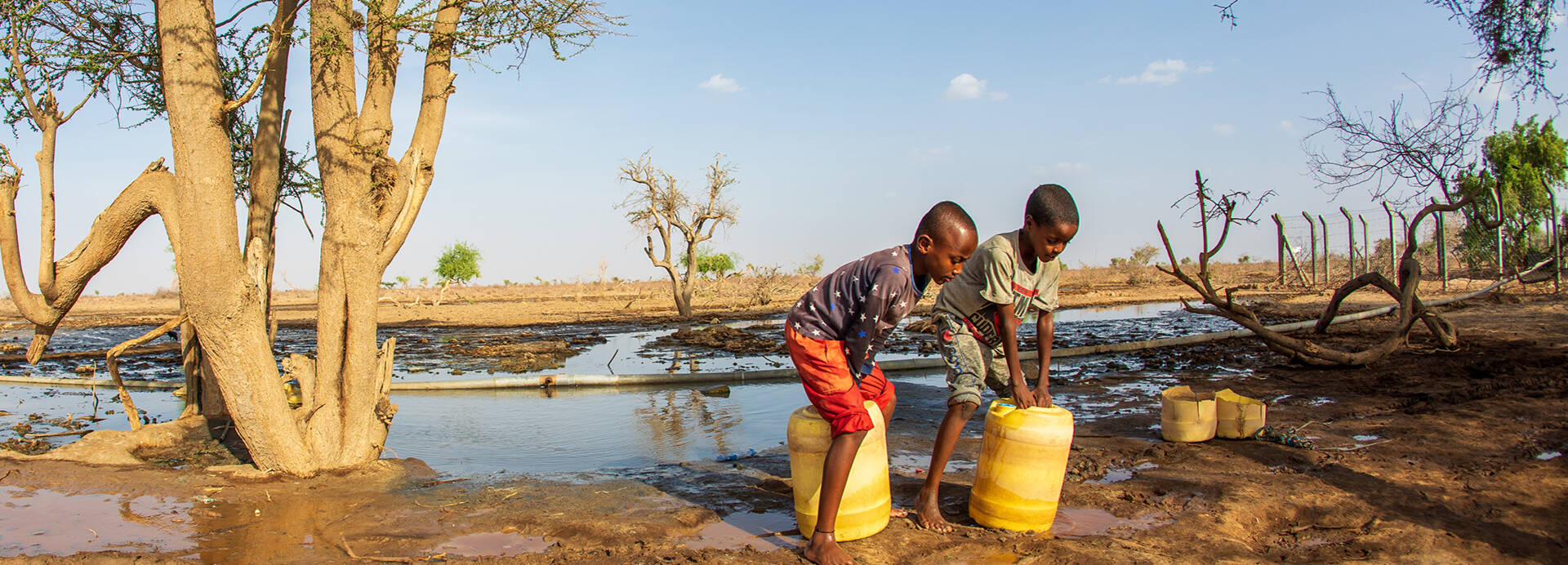 Zwei Kinder aus Kenia beim Wasser holen mit gelben Kanistern