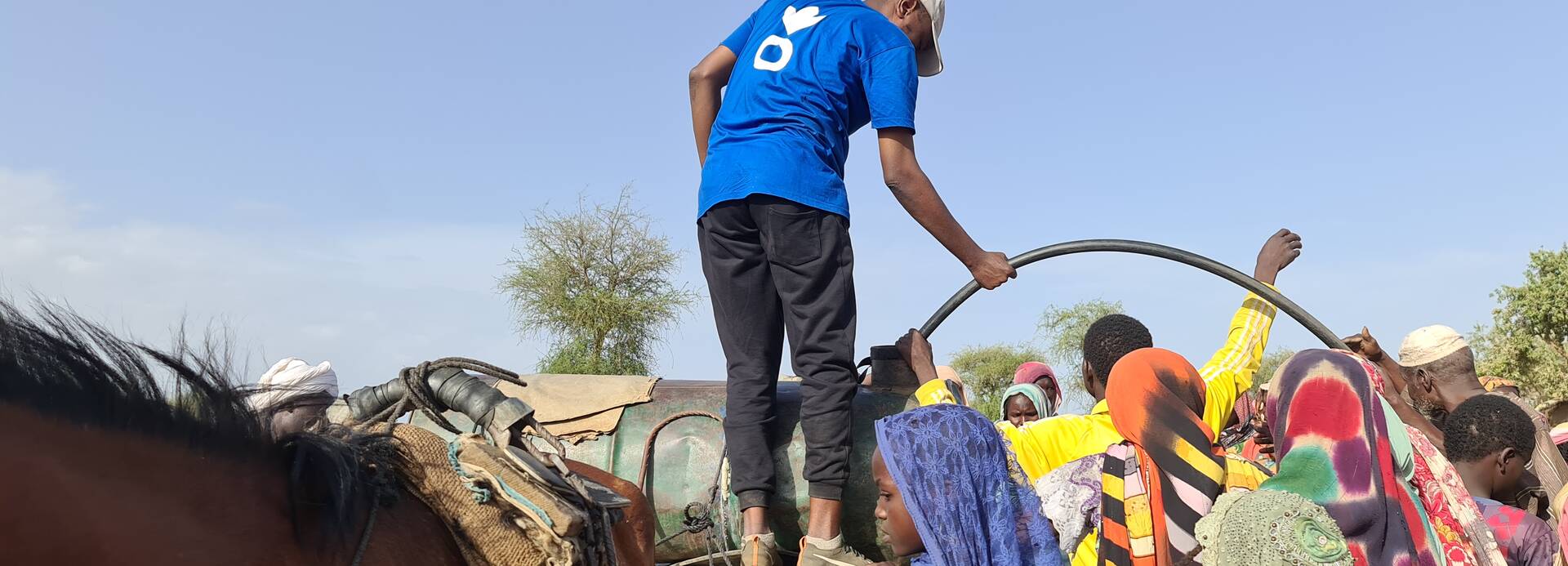 Ein Mitarbeiter von Aktion gegen den Hunger beim Verteilen von sauberem Wasser an geflüchtete Menschen aus dem Sudan im Tschad.