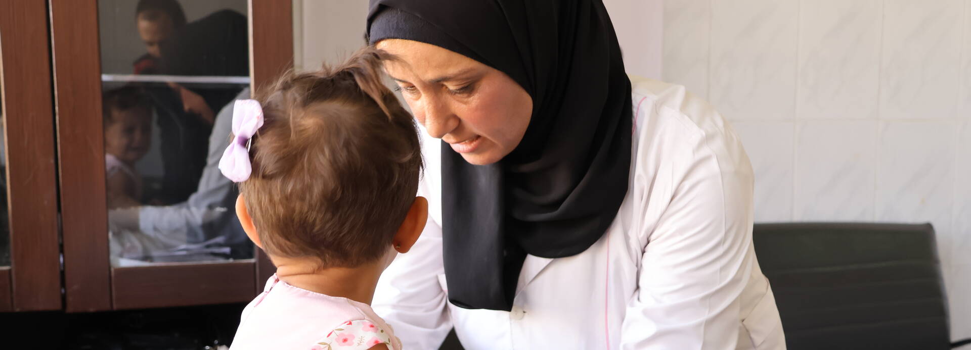Eine Gesundheitshelferin in unseren mobilen Kliniken in Syrien untersucht ein Kleinkind.