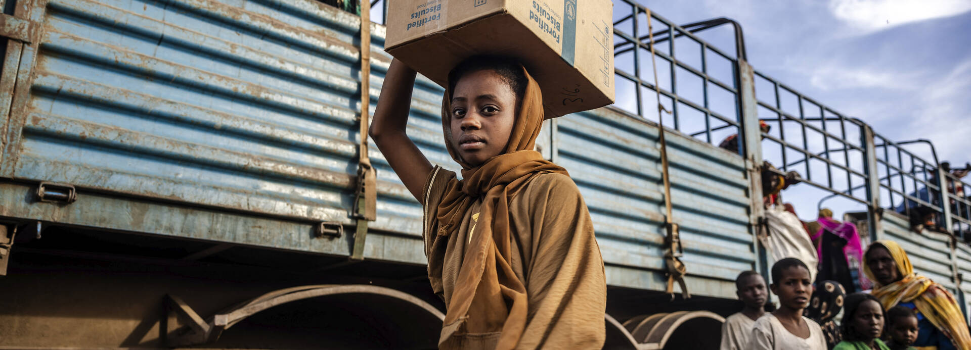 Ein Mädchen aus dem Sudan trägt einen Karton auf dem Kopf bei der Flucht in den Südsudan.