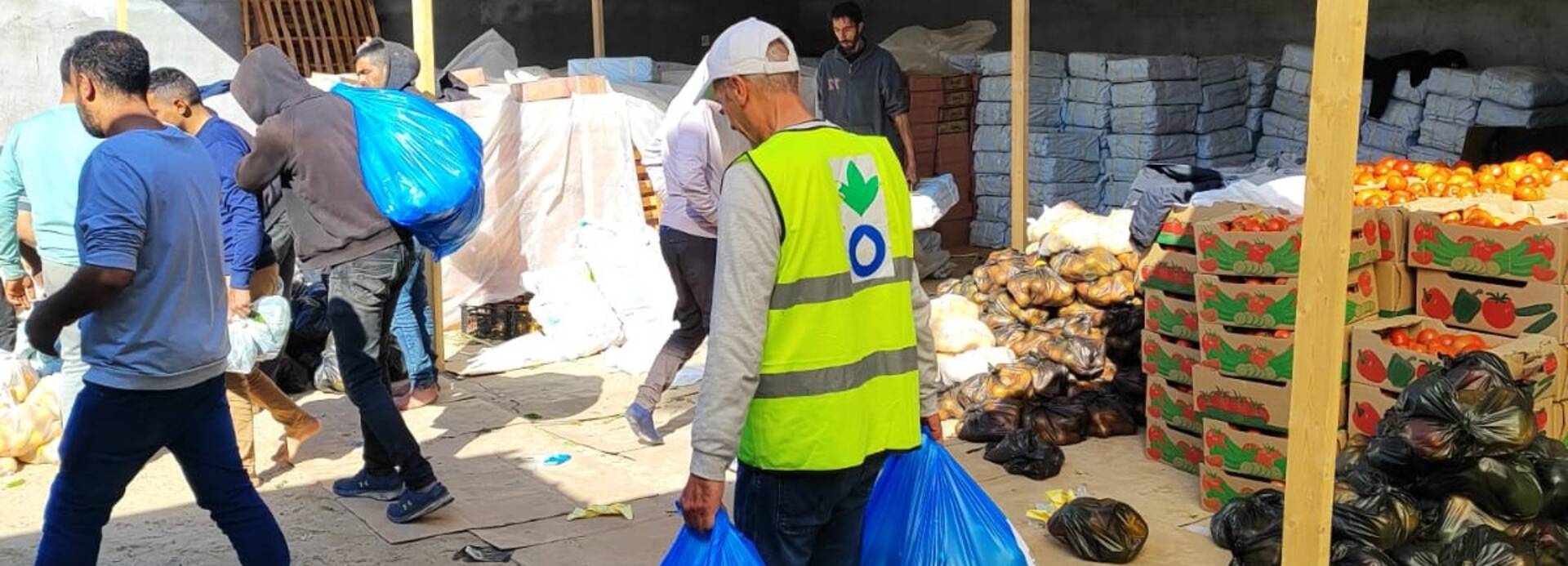 Ein Mitarbeiter von Aktion gegen den Hunger trägt Tüten aus einem Lebensmittellager zusammen mit anderen Helfenden in Rafah im Süden Gazas.