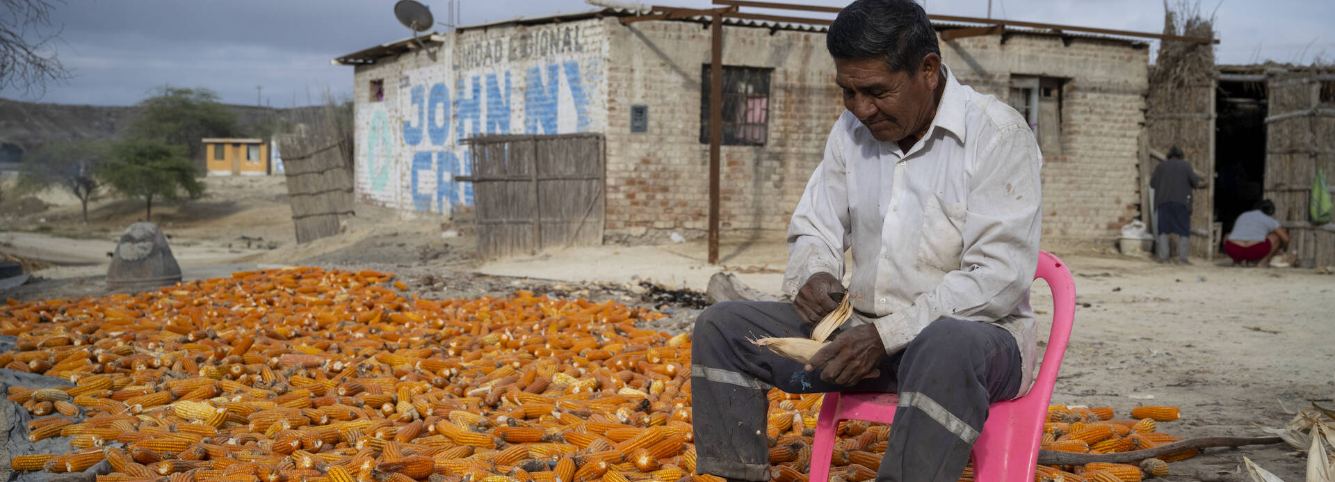 Aktion gegen den Hunger unterstützt Menschen in Peru und weltweit beim nachhaltigen und selbstständigen Aufbau einer Lebensgrundlage, die den Menschen mehr Ernährungssicherheit gibt Ein Mann sitzt auf einem Stuhl in Piura, im Norden Perus, und schält Mais.