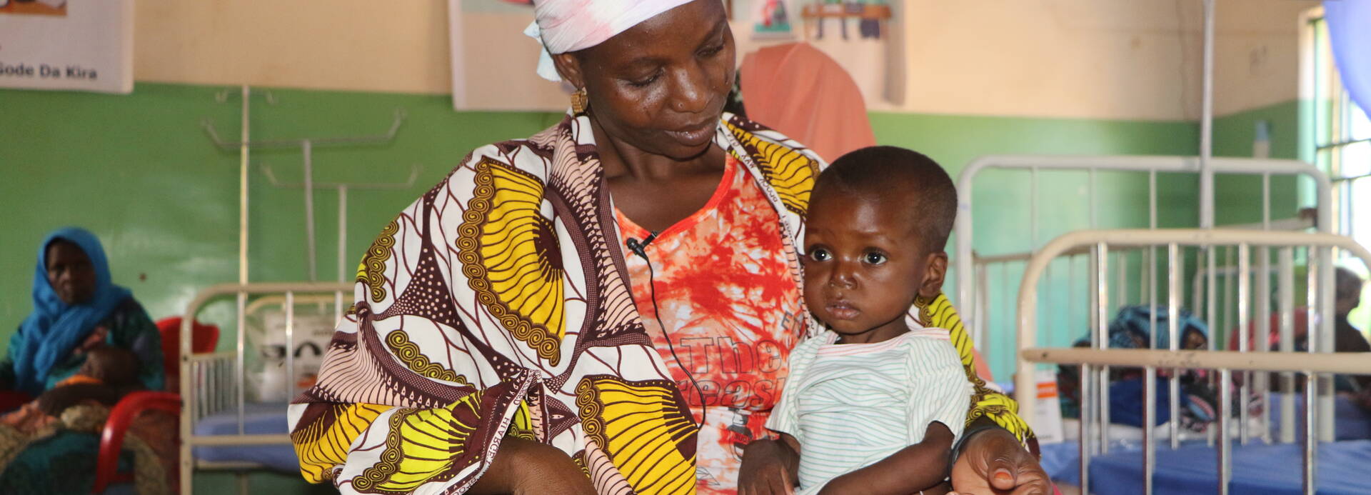 Eine Mutter sitzt mit ihrem Kind auf einem Stuhl in einem stationären Ernährungszentrum in Niger. Eine Mutter sitzt mit ihrem Kind auf einem Stuhl in einem stationären Ernährungszentrum in Niger.