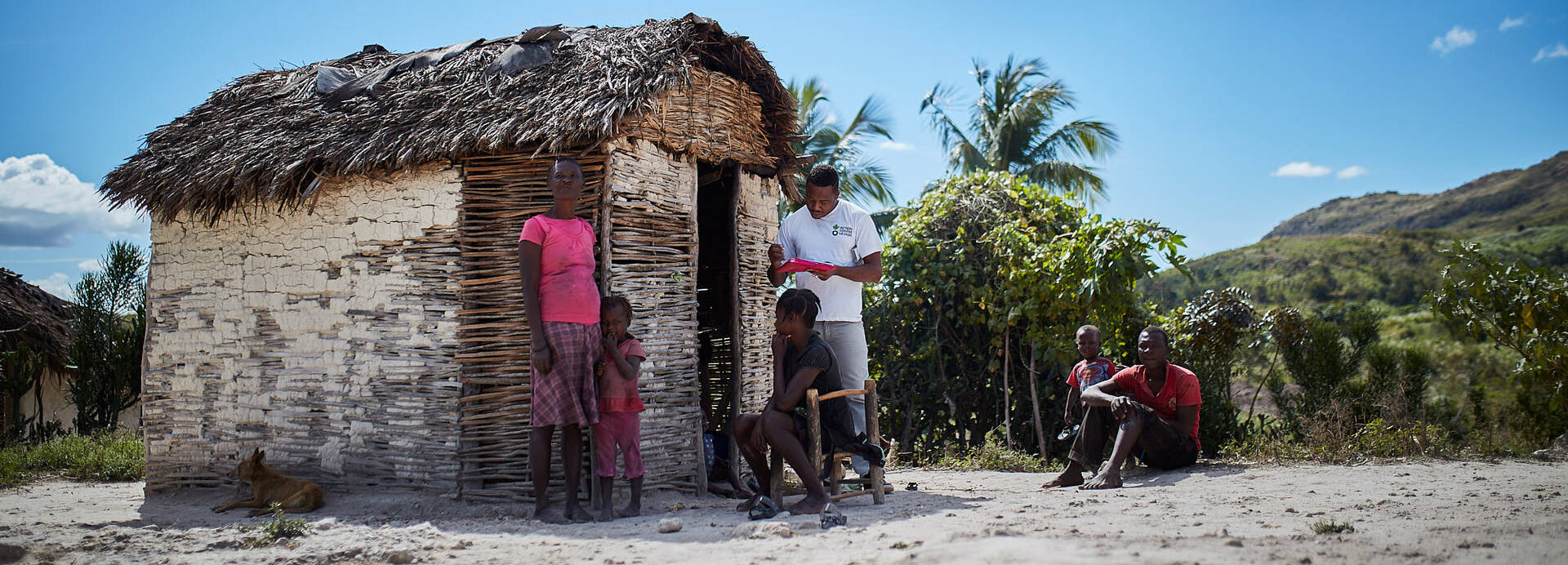 Ein Mitarbeiter von Aktion gegen den Hunger spricht vor einer kleinen Hütte mit einer Familie aus Haiti. Ein Mitarbeiter von Aktion gegen den Hunger spricht vor einer kleinen Hütte mit einer Familie aus Haiti.