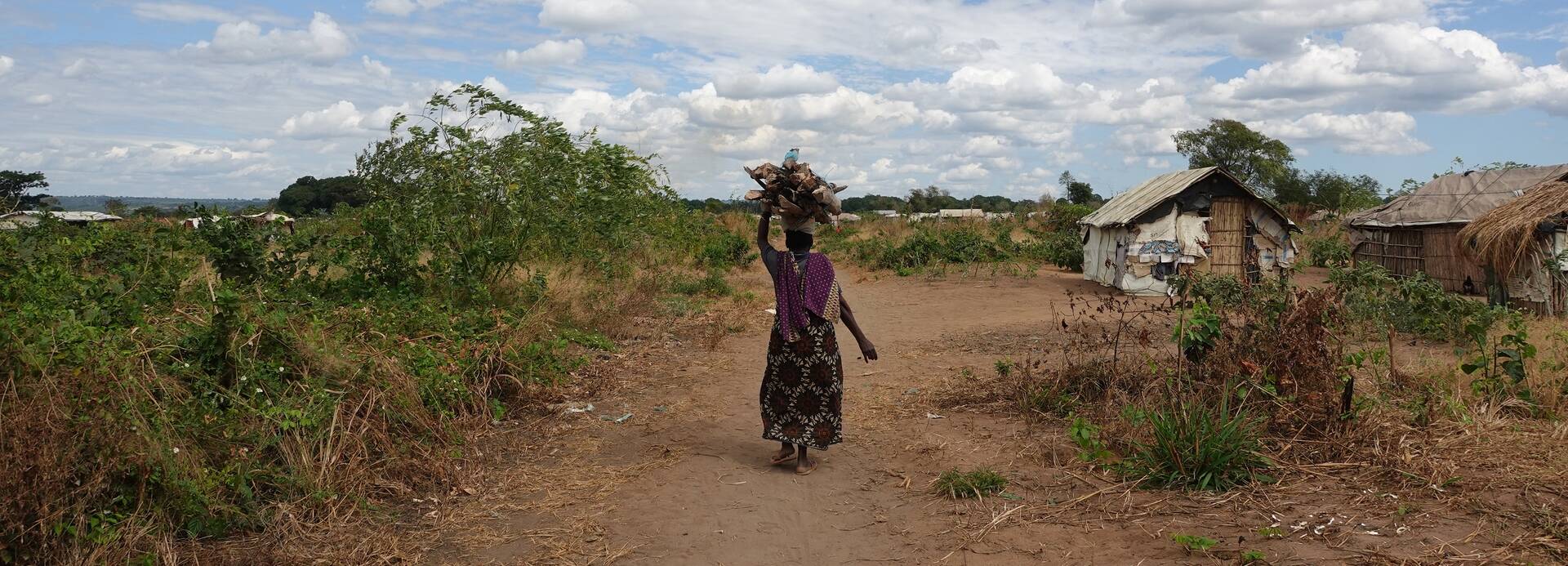 Eine Bewohnerin des Lianda-IDP-Lagers im Distrikt Mueda in Mosambik Eine Bewohnerin des Lianda-IDP-Lagers im Distrikt Mueda in Mosambik läuft einen unbefestigten Weg entlang.