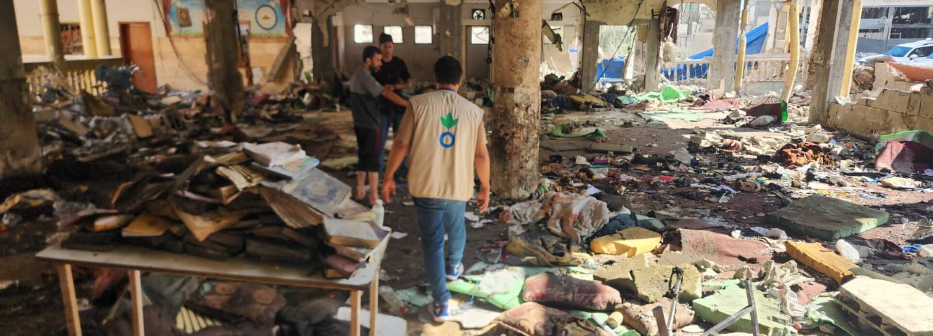 Ein Mitarbeiter steht mit weiteren Menschen in einem zerstörten Schulgebäude in Gaza Stadt. Ein Mitarbeiter steht mit weiteren Menschen in einem zerstörten Schulgebäude in Gaza Stadt.