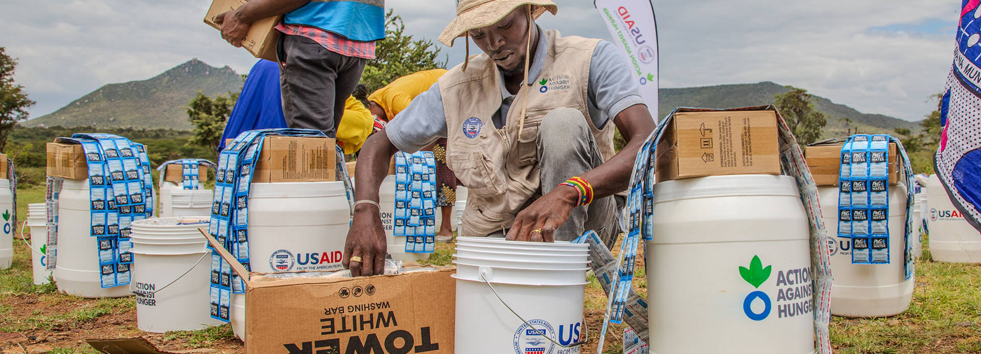 Einer unserer Mitarbeiter in Kenia füllt Hilfsgüter in Eimer mit der Aufschrift "Aktion gegen den Hunger" und "USAID". Einer unserer Mitarbeiter in Kenia füllt Hilfsgüter in Eimer mit der Aufschrift "Aktion gegen den Hunger" und "USAID".