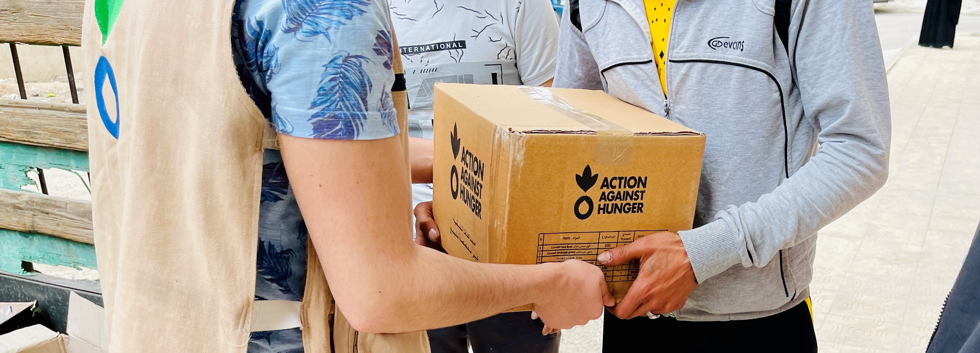 Ein Mitarbeiter von Aktion gegen den Hunger übergibt in Syrien ein Paket mit Nahrungsmitteln an einen jungen Mann. Ein Mitarbeiter von Aktion gegen den Hunger übergibt in Syrien ein Paket mit Nahrungsmitteln an einen jungen Mann.