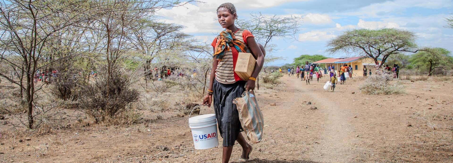 Eine Frau trägt einen Wasserkanister mit der Aufschrift "USAID". Eine Frau trägt einen Wasserkanister mit der Aufschrift "USAID".