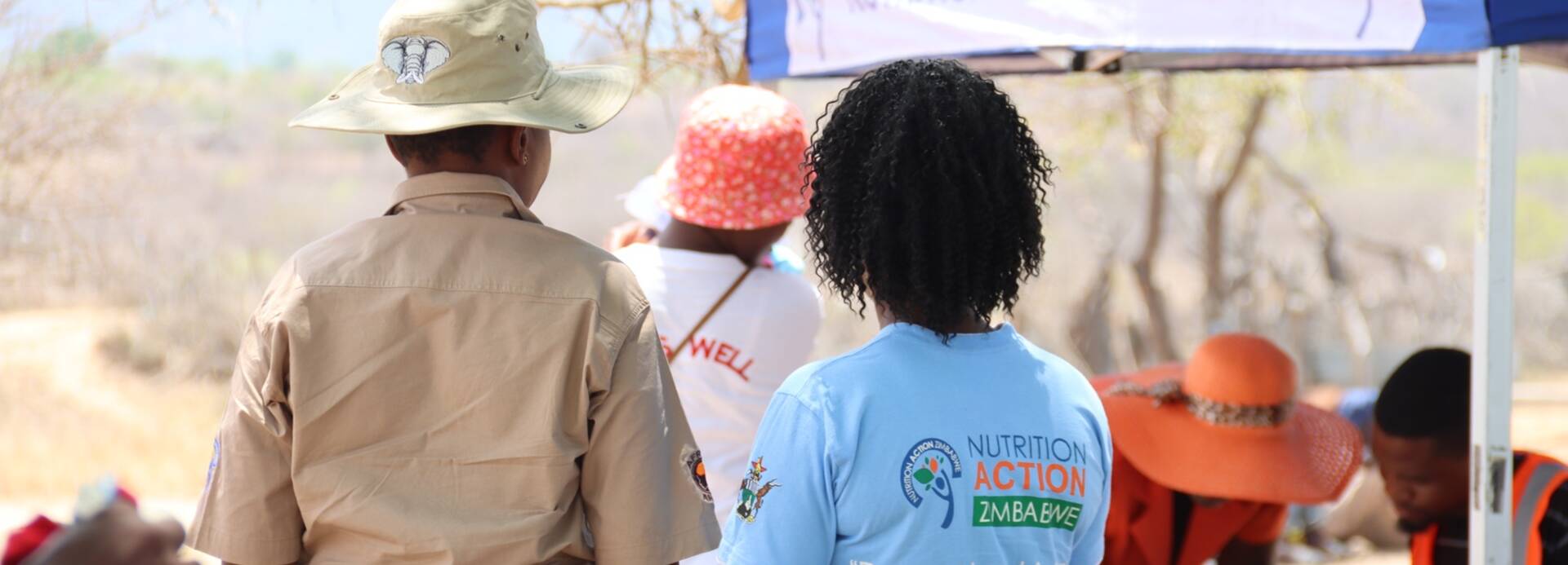 Unsere lokalen Projektmitarbeiter*innen vor einem Notfallzelt im Rahmen humanitärer Hilfe in Simbabwe