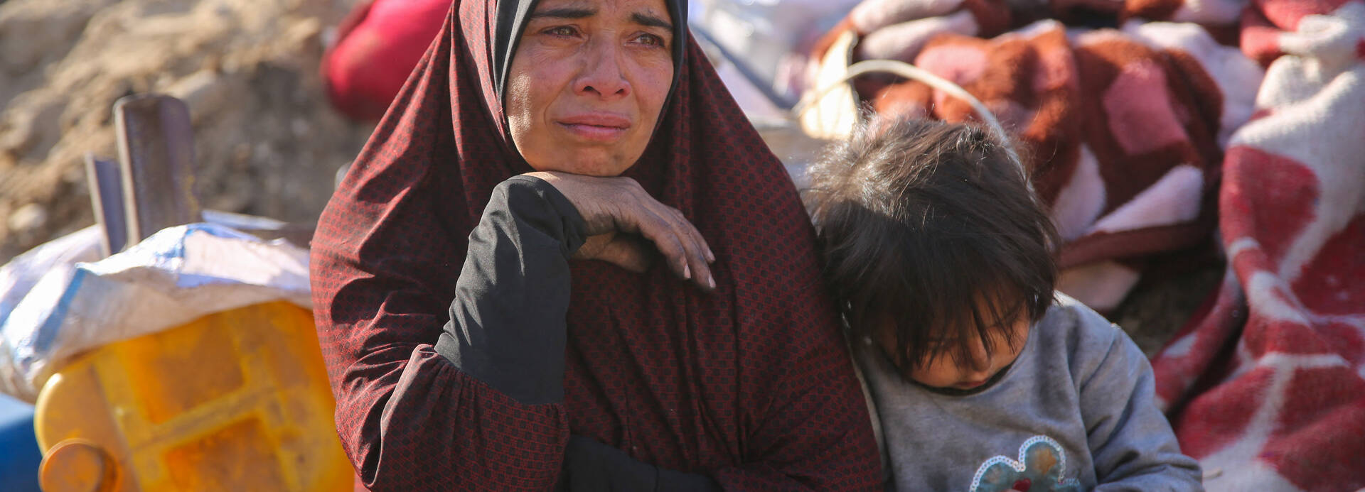 Eine Frau und ein Kind sitzen auf Decken im zerstörten Gazastreifen Eine Frau und ein Kind sitzen auf Decken im zerstörten Gazastreifen