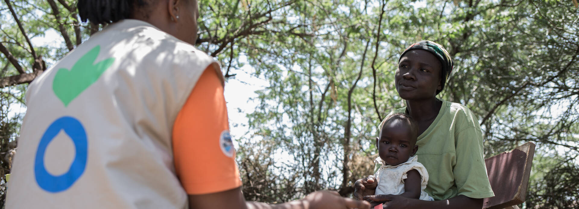 Mitarbeiterin von Aktion gegen den Hunger spricht mit einer Mutter über die Ernährung ihres Kindes in Kenia.