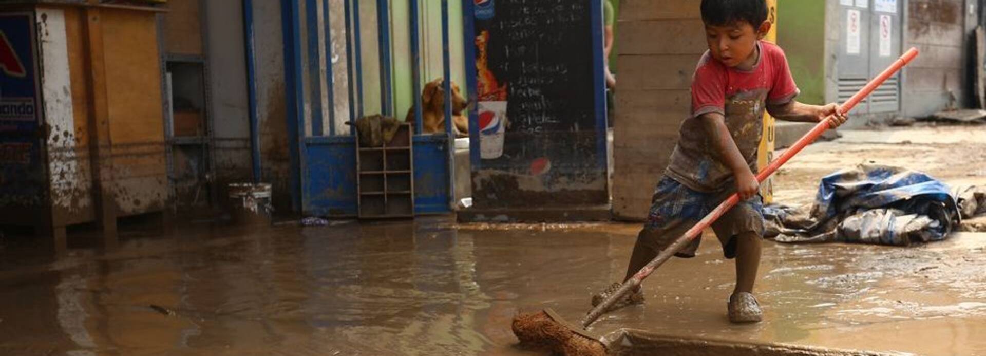 Junge kehrt Schlamm nach Überschwemmung in Peru