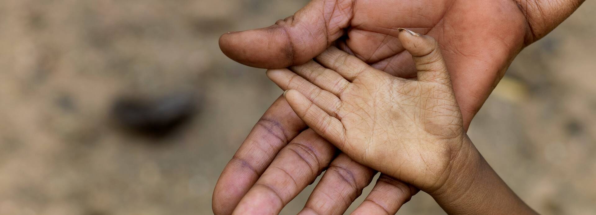Eine Kinderhand liegt in der Hand eines Erwachsenen.