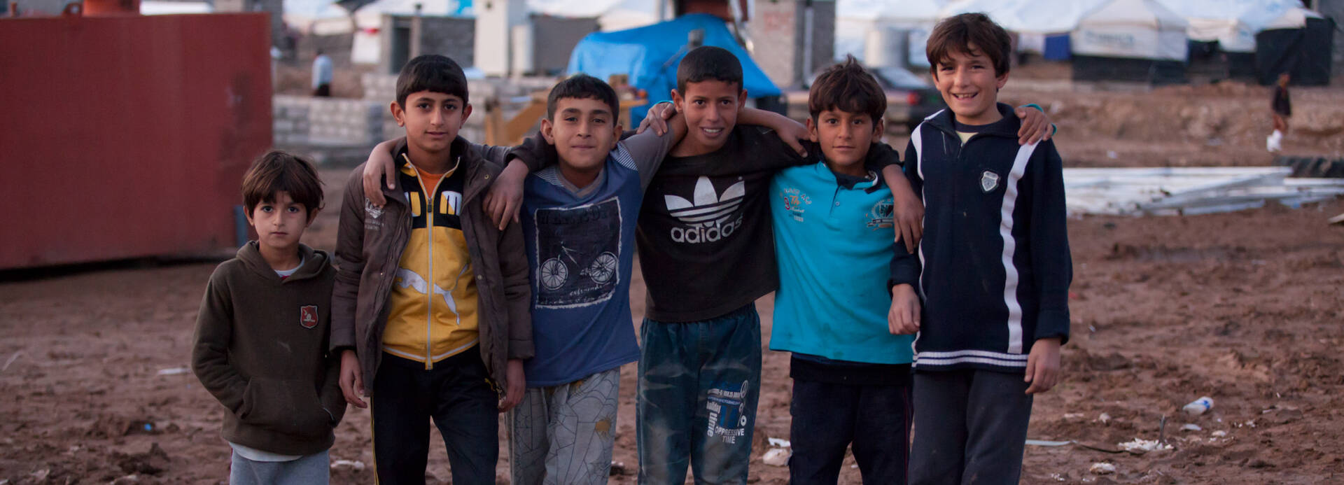 Eine Gruppe Jugendlicher vor der Zeltlandschaft eines Flüchtlingscamps.