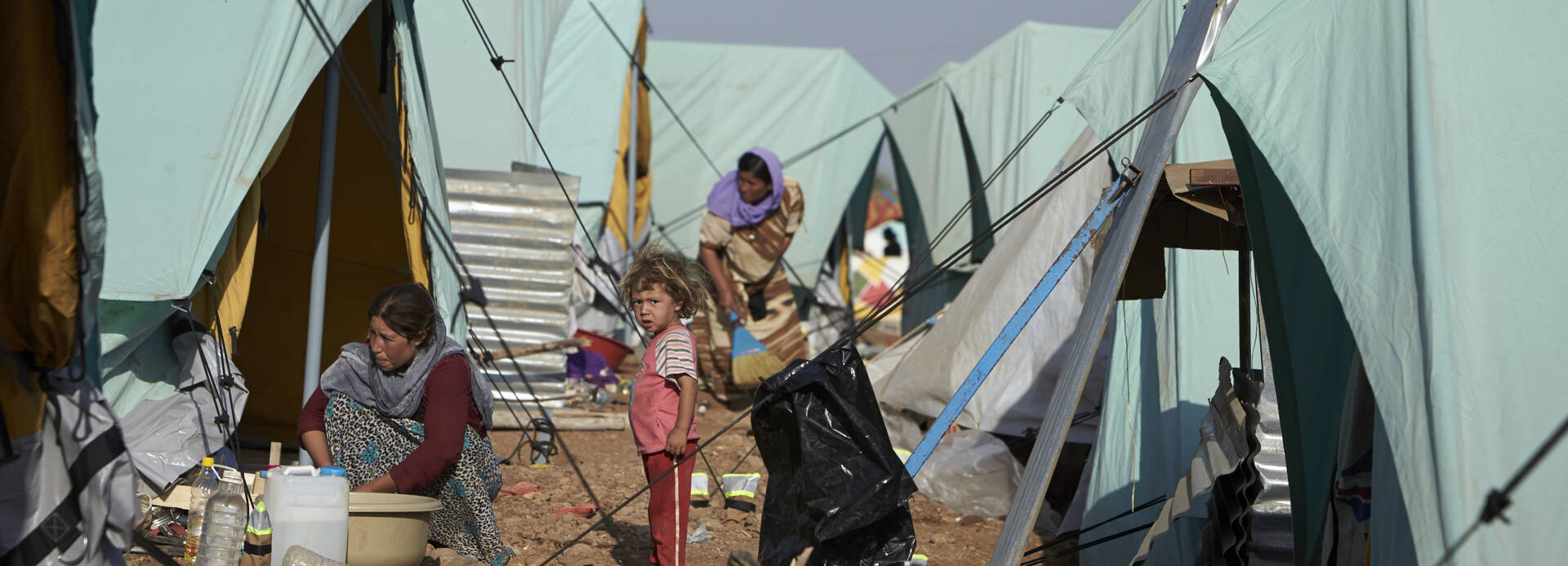 Kind steht inmitten von Zelten eines Flüchtlingslagers.