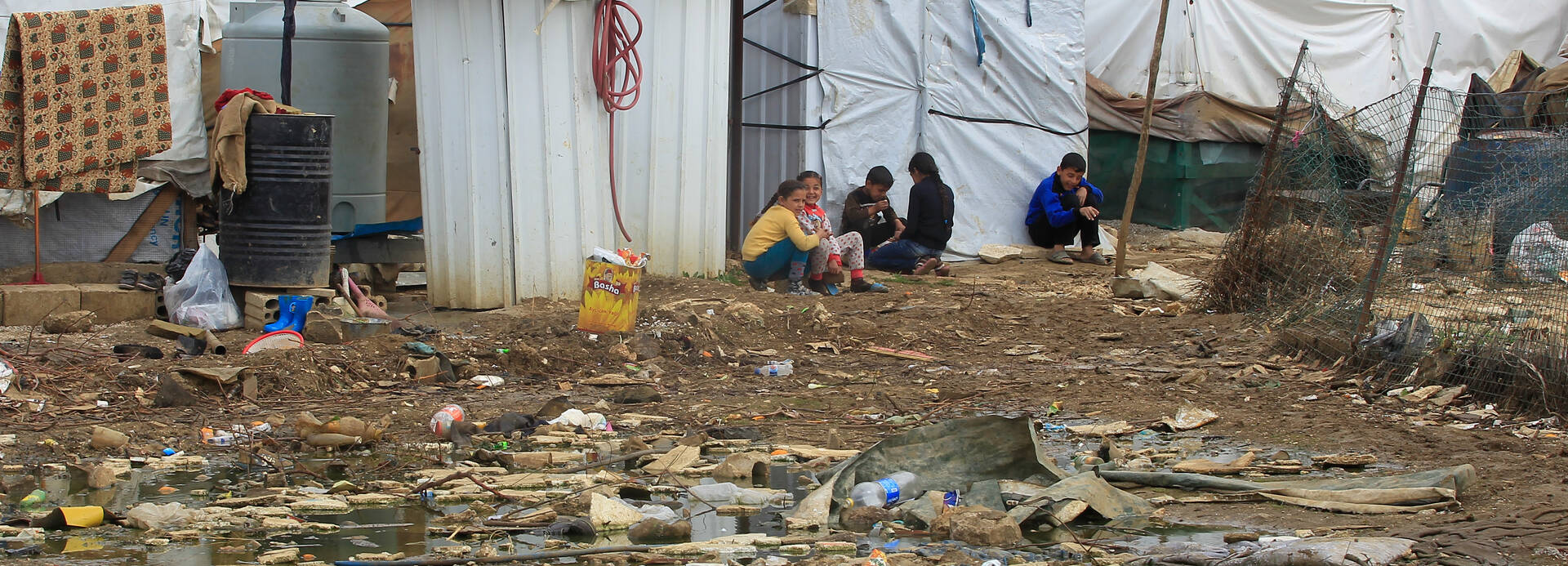 Syrische Flüchtlingskinder sitzen auf dem Boden in einem Flüchtlingslager