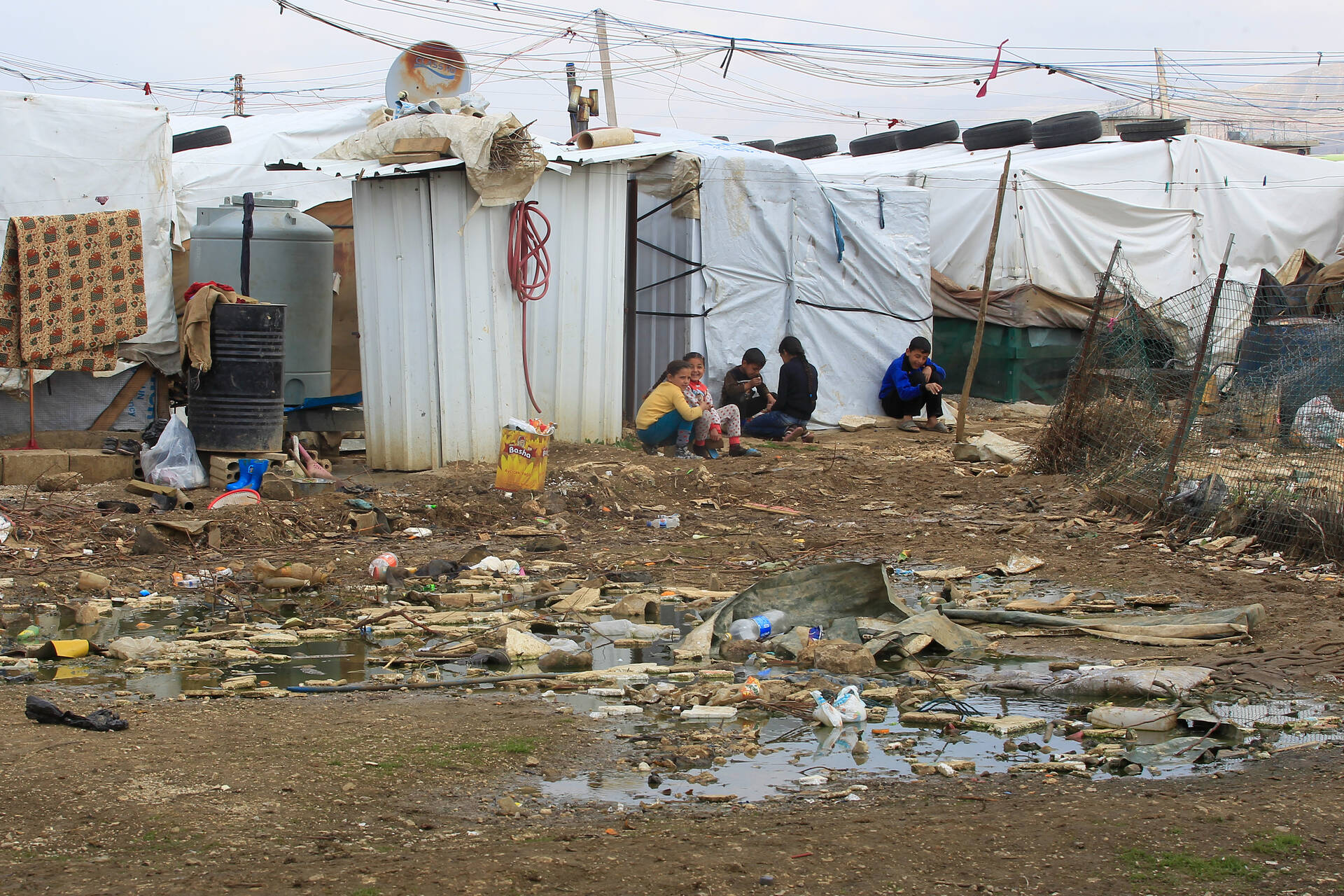 Syrische Flüchtlingskinder sitzen auf dem Boden in einem Flüchtlingslager