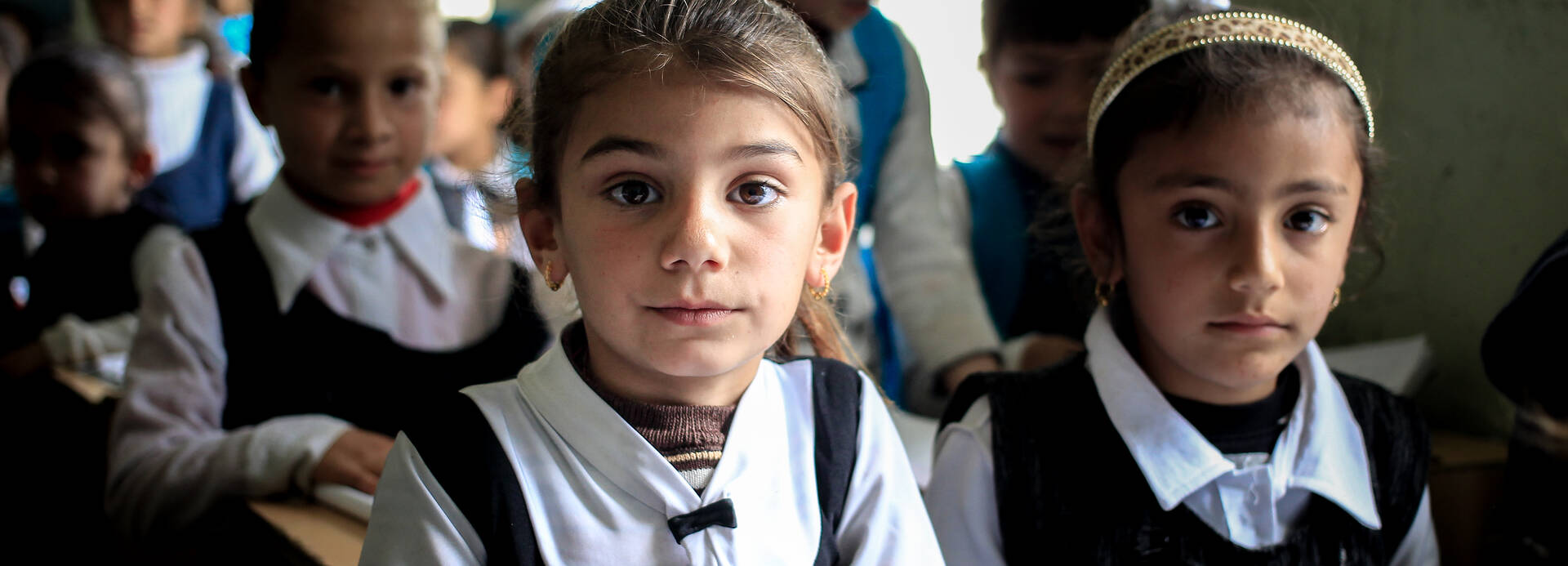 Ein Mädchen im Irak freut sich, dass sie in einer Schule ist und lernen darf.