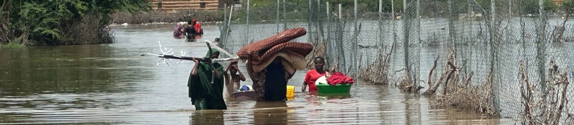Eine Familie aus Somalia versucht, zumindest einen Teil ihrer Habseligkeiten vor den Überflutungen zu retten. Sie laufen durchs hüfthohe Wasser.