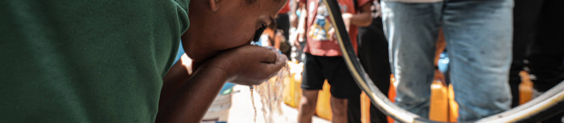 Ein Kind trinkt im Norden Gazas frisches Wasser aus einem Schlauch, den ein Mitarbeiter von Aktion gegen den Hunger hält. Ein Kind trinkt im Norden Gazas frisches Wasser aus einem Schlauch, den ein Mitarbeiter von Aktion gegen den Hunger hält.