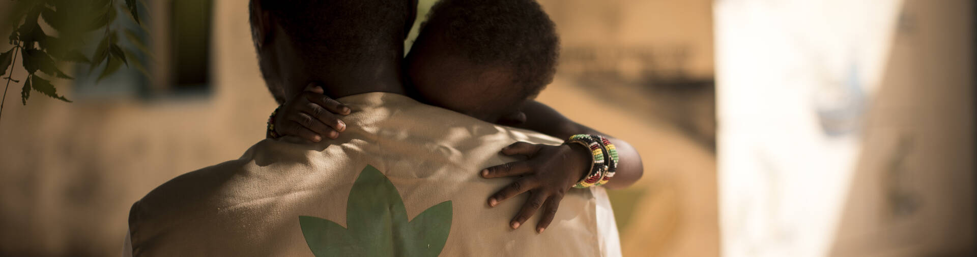 Mitarbeiter aus Mali hat Kind auf dem Arm Mitarbeiter aus Mali hat Kind auf dem Arm