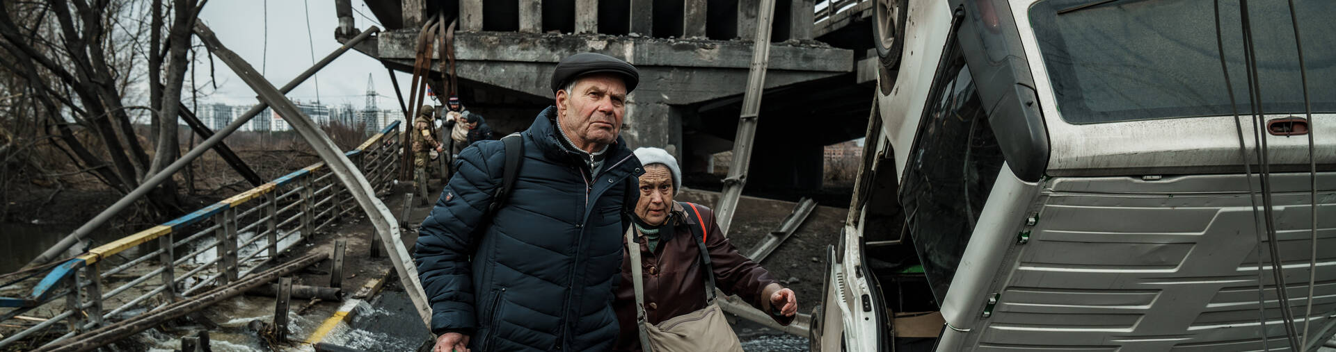 Ein älteres Ehepaar flüchtet durch die Trümmer in Irpin in der Ukraine.