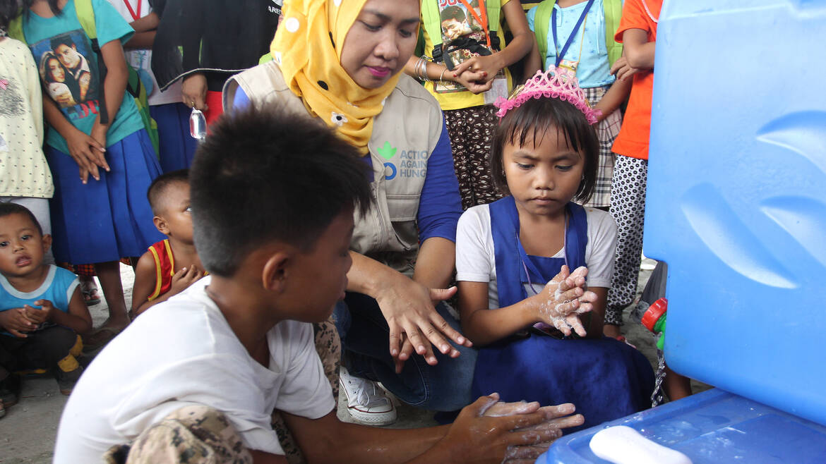 Mitarbeiterin von Aktion gegen den Hunger erklärt richtiges Händewaschen