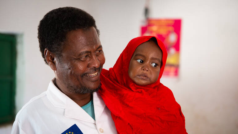 Gesundheitspfleger Mohamed mit Halima auf dem Arm