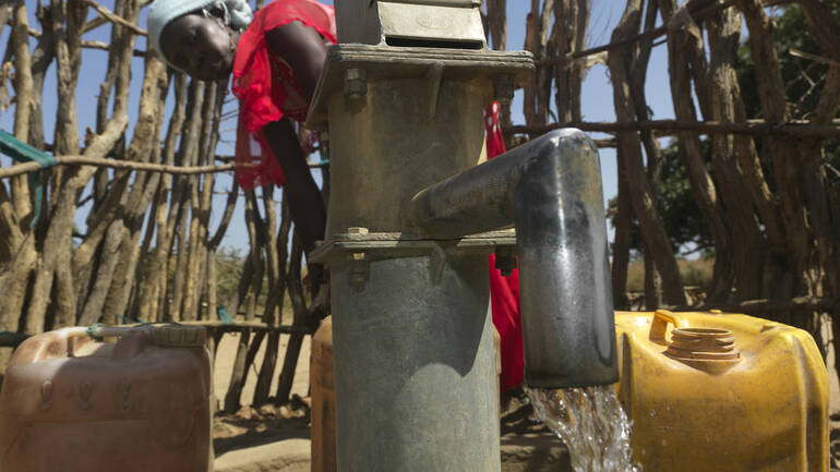 Frau pumpt Wasser aus einem Brunnen im Südsudan