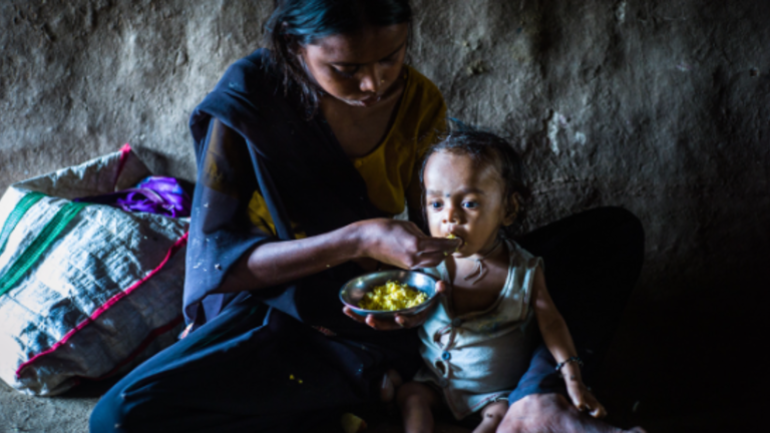 Mutter füttert ihr mangelernährtes Kind in Nepal 