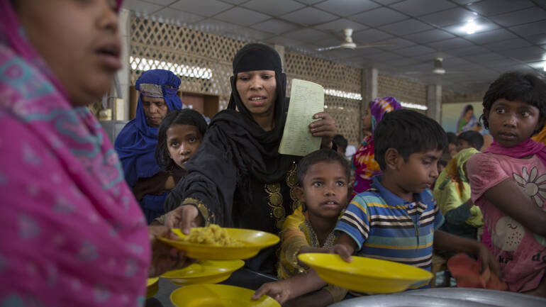 Mitarbeiterin von Aktion gegen den Hunger verteilt Essen im Rohingya Geflüchtetenlager in Bangladesch