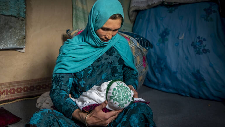 Nadia aus Daykundi in Afghanistan hält ihr jüngstes Kind auf dem Schoß