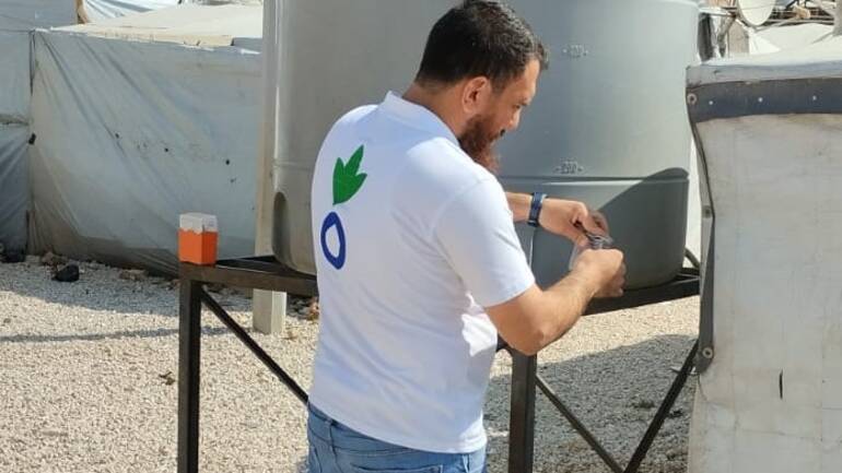 Ein Mitarbeiter von Aktion gegen den Hunger führt eine Wassermessung an einem Wassertank durch