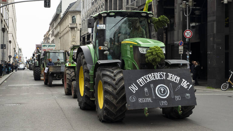 Ein Traktor bei der "Wir haben es satt"-Demo mit dem Schild "Du entscheidest jeden Tag! Regional und Bio"