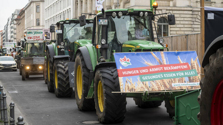Traktorenprotest auf der "Wir haben es satt!"-Demo 2023: Trecker mit Schild "Hunger und Armut bekämpfen! Gesundes Essen für alle!"