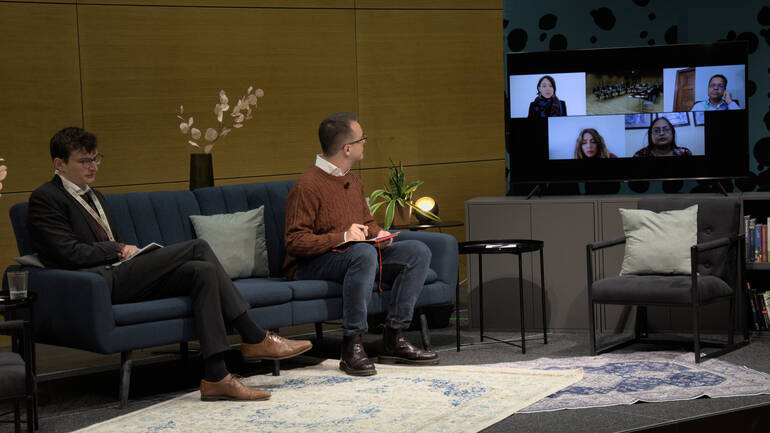 Zwei Panelisten auf dem blauen Sofa hören den teilnehmenden Expert*innen am Bildschirm zu.